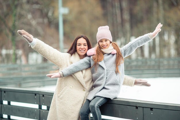 Little adorable girl with her mother skating on ice-rink