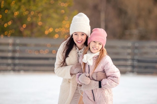 Little adorable girl with her mother skating on ice-rink