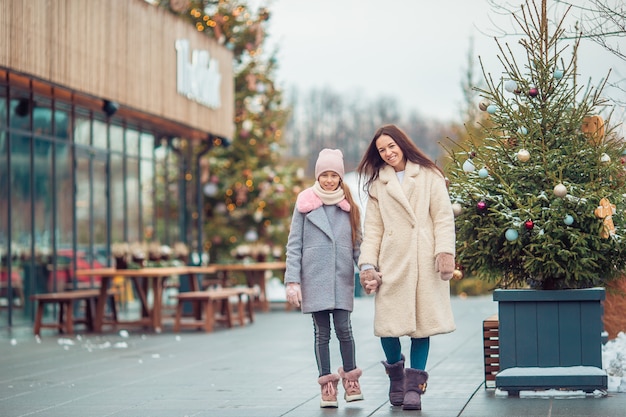 Little adorable girl with her mother skating on ice-rink