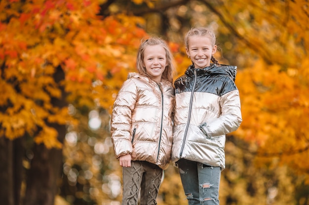 Little adorable girls outdoors at warm sunny autumn day