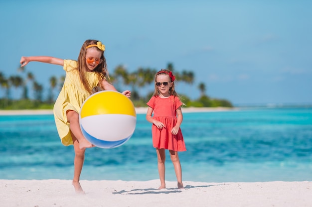 Piccole ragazze adorabili che giocano sulla spiaggia con la palla di aria