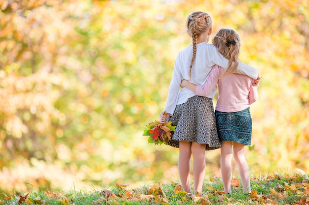 Le piccole ragazze adorabili al giorno caldo in autunno parcheggiano all'aperto