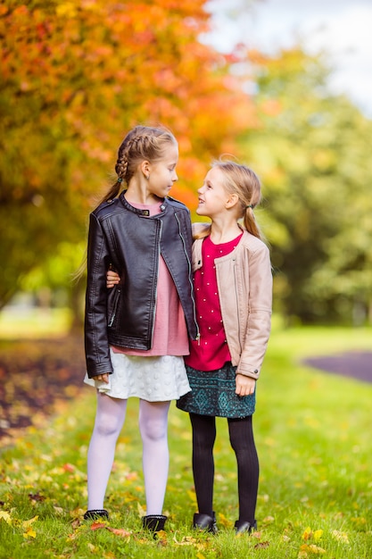 Little adorable girls at warm day in autumn park outdoors