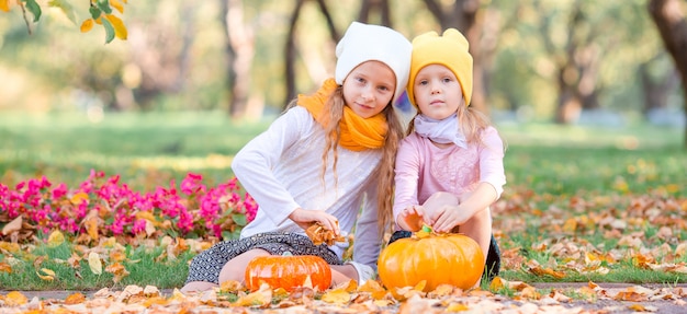 Little adorable girls at warm day in autumn park outdoors