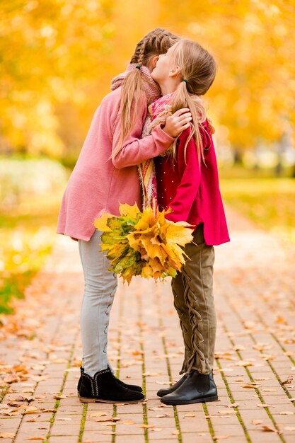 Little adorable girls at warm day in autumn park outdoors