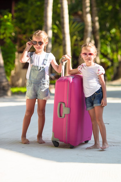 Photo little adorable girls with big suitcase on tropical white beach during summer vacation