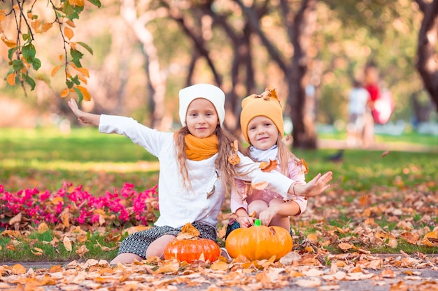 Little adorable girls with pumpkin outdoors on a warm autumn day.