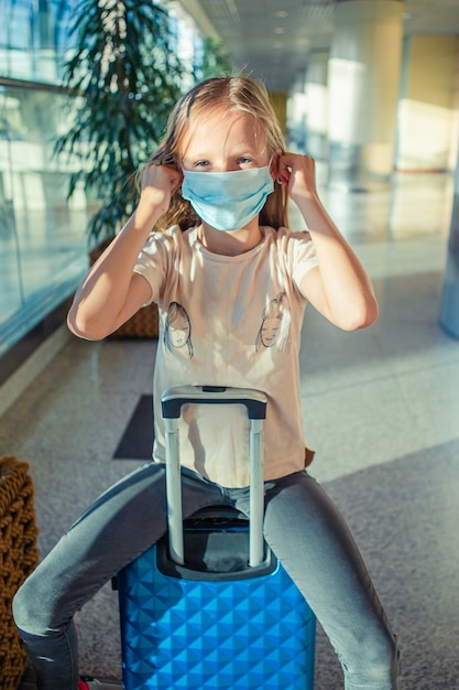 Piccolo bambino adorabile con protezione facciale maschera chirurgica all'aeroporto internazionale. protezione contro coronavirus e gripp