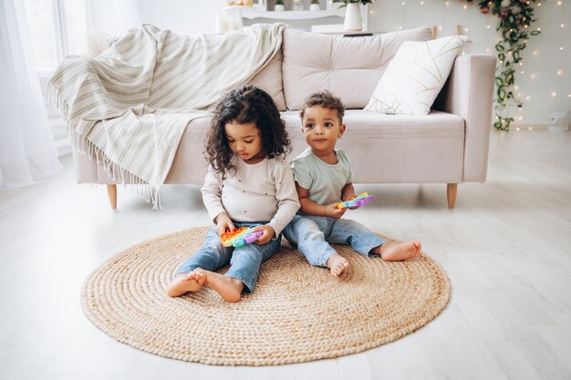 Little African American black children playing with pop toys on the floor at home