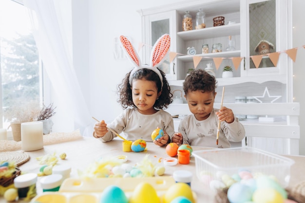 Little African American boy and girl paint Easter eggs at home black children are preparing for Easter