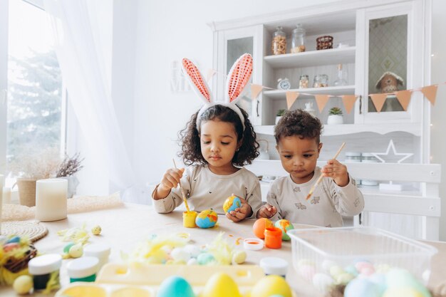 Little African American boy and girl paint Easter eggs at home black children are preparing for Easter