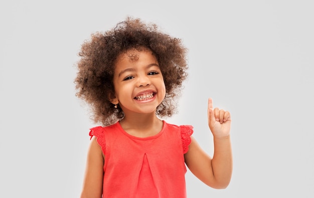 Foto piccola ragazza afroamericana che indica il dito in alto.