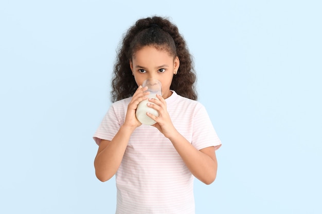 Little African-American girl with milk on color