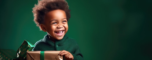 A little african boy is unwrapping a gift and laughs on green background Banner copy space Generative ai