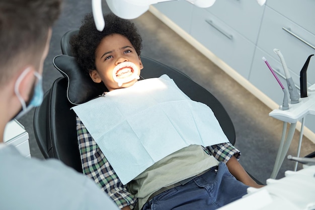 Little african boy waiting for medical procedure of bleaching teeth