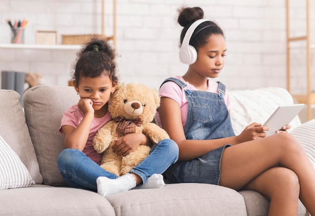 Photo little african girl boring alone her elder sister watching videos