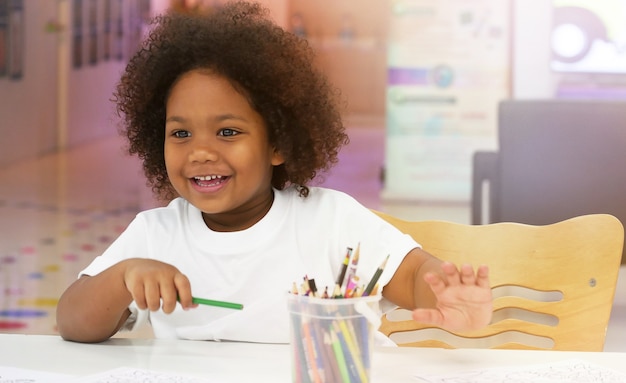 Little African girl smiling while drawing with happiness.