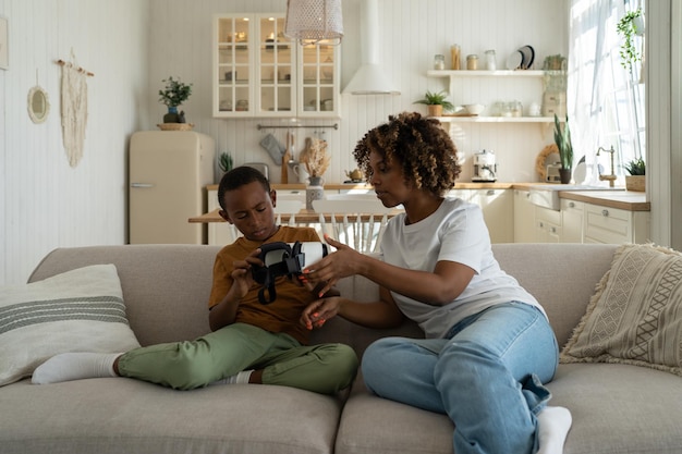 사진 작은 아프리카 소년은 집에서 엄마와 함께 소파에 앉아서 처음으로 vr을 경험합니다.