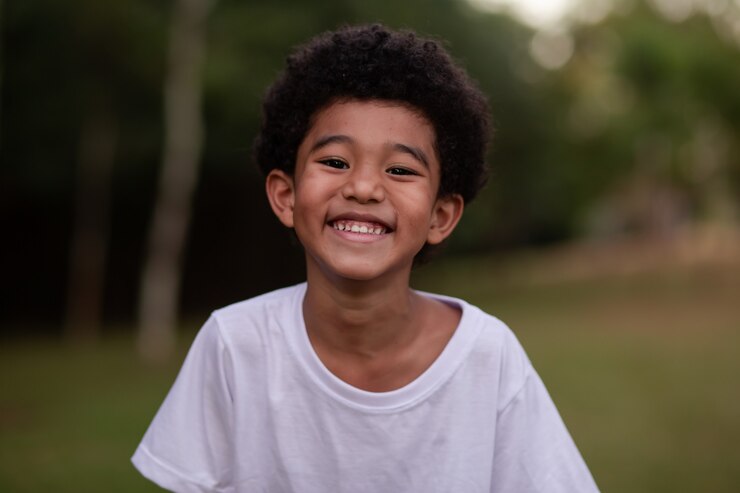Little afro boy smiling at camera in the park