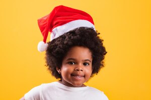 非洲式发型的小女孩照片孩子圣诞老人的帽子对着镜头微笑