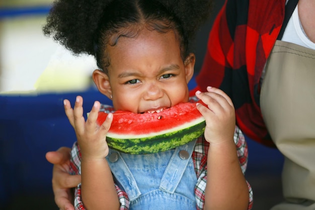 Little afro girl enjoy eating watermelon in plantation at organic farm