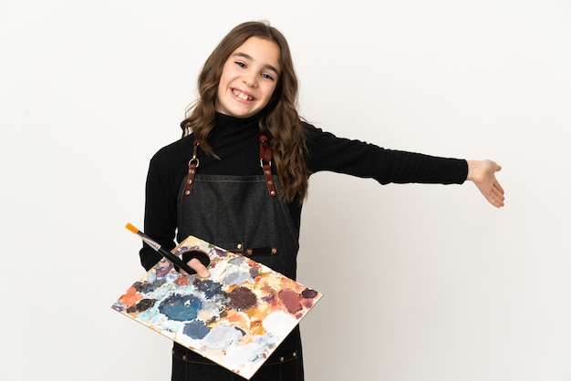 Little artist girl holding a palette isolated on white wall extending hands to the side for inviting to come