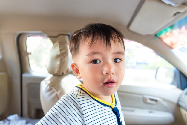 Foto piccolo ragazzo asia guardando qualcosa in auto di sicurezza per il viaggio.