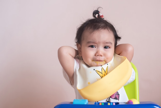 小さなアジアの女の赤ちゃんの食事の時間、悲しみ、赤ちゃんの表現の概念の不幸な顔