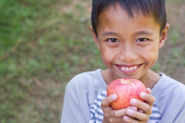 リトルアジアの少年はリンゴを食べることを楽しむ。