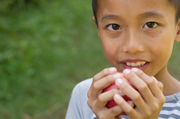 リトルアジアの少年はリンゴを食べることを楽しむ。