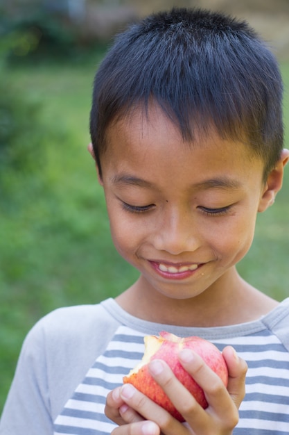 Photo little asian boy enjoy eat an apple.