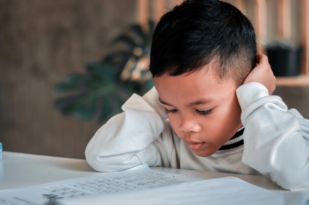 Il ragazzino asiatico ha sottolineato stanco frustrato annoiato dallo studio. bambini con espressione infelice.