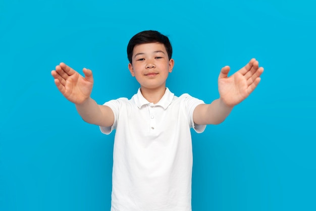 Photo little asian boy in white tshirt hugging and taking care of you on blue background korean child