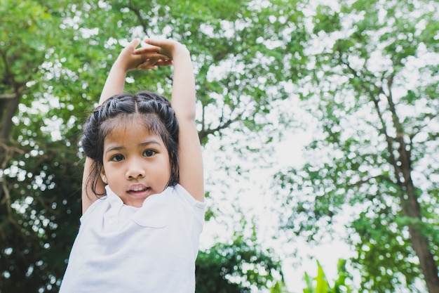 Little asian child girl doing yoga in the public park.