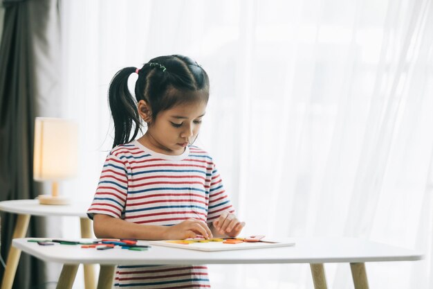 Little asian child girl drawing with colorful crayons at home