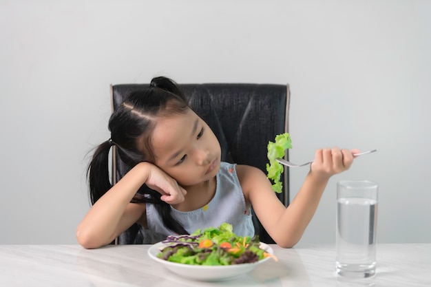 Little asian cute girl refuses to eat healthy vegetablesNutrition healthy eating habits for kids conceptChildren do not like to eat vegetables