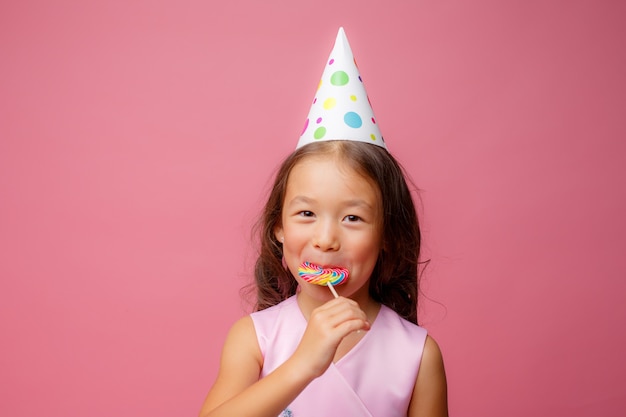 little  Asian girl, at a birthday party, a Lollipop, on a pink 