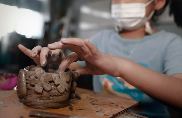 Little Asian girl creating potter clay bowl at homeEducationhobby and handicraft concept