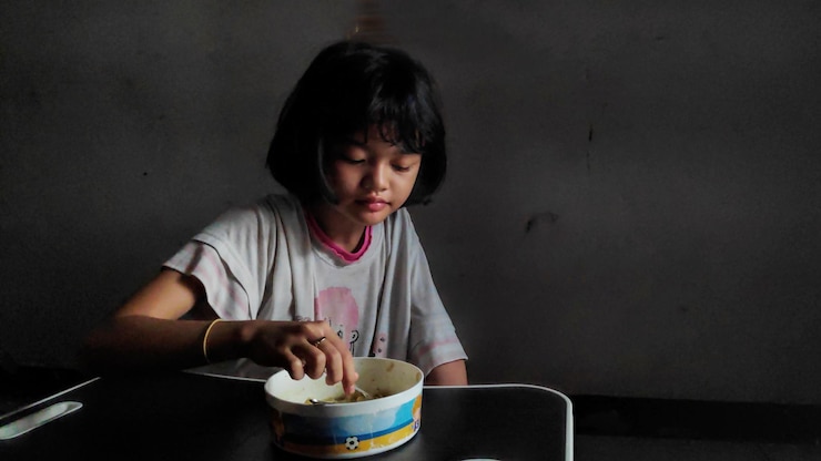 Photo アジアの女の子は昼食の時間に鉢の上でヌードルを食べるのを楽しんでいます美味しい顔