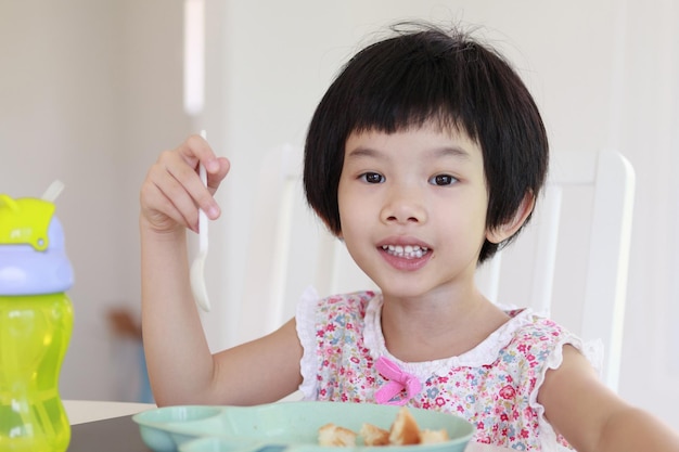 朝食を食べている小さなアジアの女の子