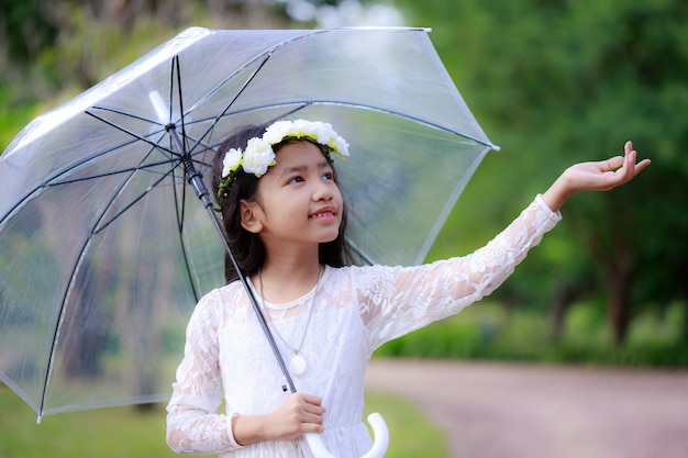 写真 明確な傘を押しながら幸せに笑みを浮かべて小さなアジアの女の子