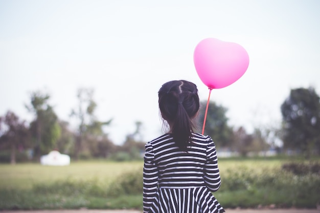 Photo little asian girl holding pink balloon in hand