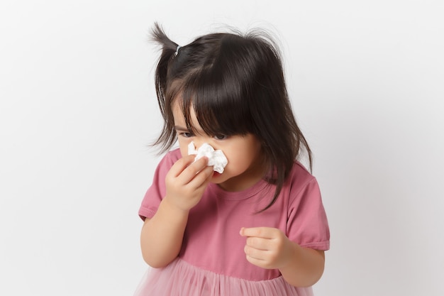 Little asian girl holding a tissue and blow her nose. Kid with cold rhinitis. 