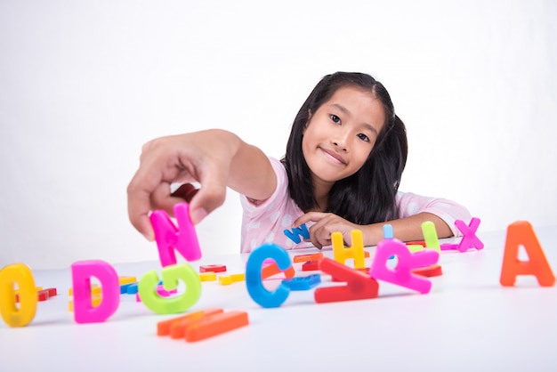 Маленькая азиатская девочка учится с игрушечной моделью ABC