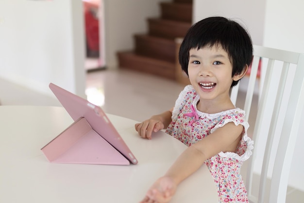 Little asian girl playing digital tablet at home