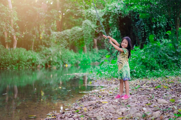 Foto piccola ragazza asiatica preparando a saltare nel fiume dalla corda oscillante