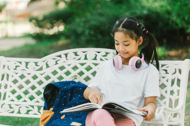 Little Asian girl reading a book in the garden Education concept