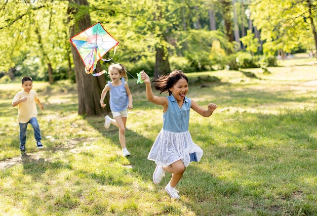 写真 公園で凧を持って楽しく走っているアジアの少女