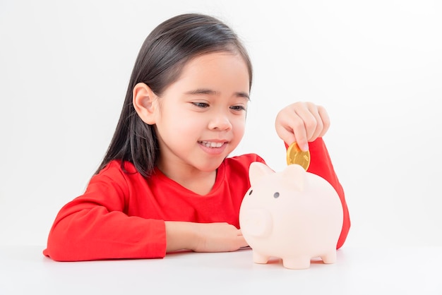 Little Asian girl saving money in a piggy bank learning about saving money for future education