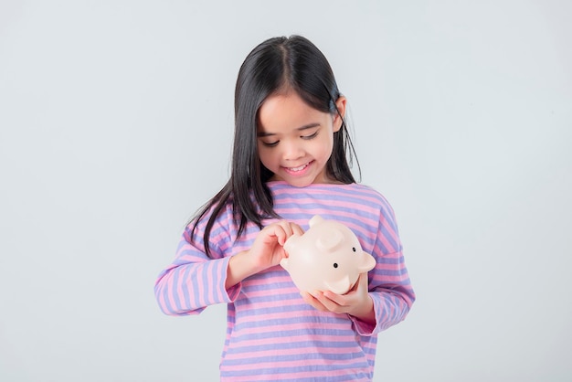 Little Asian girl saving money in a piggy bank